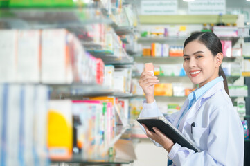 Fototapeta premium Portrait of female pharmacist using tablet in a modern pharmacy drugstore.