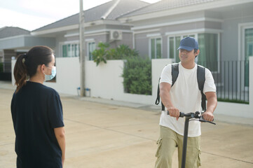 Smiling delivery man with thermal backpack riding on an electric scooter, deliver online concept