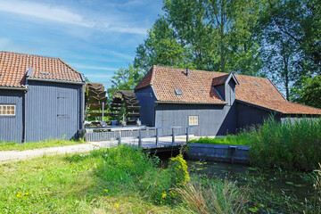 Two scenic idyllic ancient wooden gray dutch country grist and oil water mill buildings from 16th...