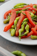 Stir-fry rat tail radish dish with red bell pepper on a plate. Vegan cuisine meal.