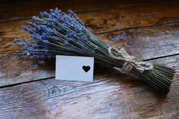 Mockup of a greeting card or card for wishes and a bouquet of lavender on a wooden background....