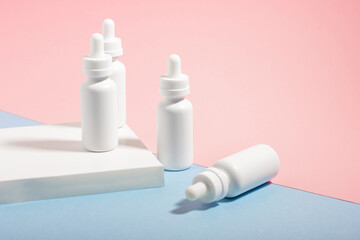 A set of white cosmetic bottles with a dropper, on a podium with hard shadows. The concept of face...