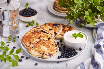 Pancakes with wild blueberries, served with sour cream and fresh berries. Healthy breakfast for the family. 
