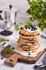 Stack of Pancakes with wild blueberries, served with sour cream and fresh berries. Healthy breakfast for the family. 