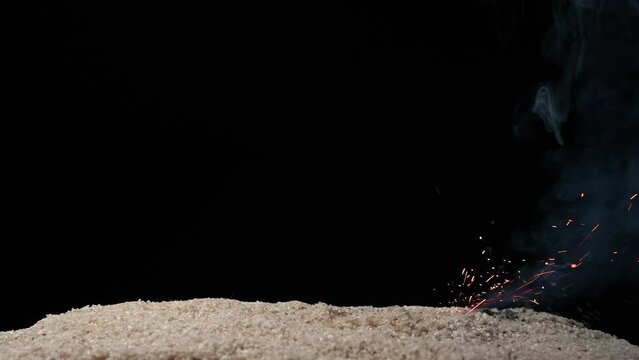 A full HD 1080p Slow motion video of a fuse wire being burnt under river sand and forming beautiful ominous smoke puffs. Taken in a studio setup with a dark black background. a very eerie ominous mood