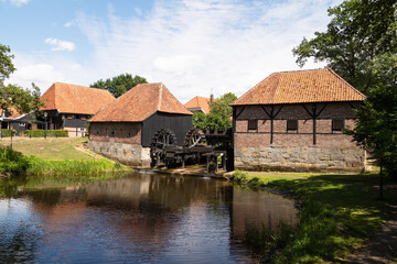 Fototapeta na wymiar Oostendorper watermill; a double, water-driven mill with three undershot wheels on the Buurserbeek south of the Dutch village of Haaksbergen in Overijssel.
