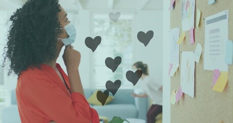 Multiple heart icons floating over african american woman reading memo notes at office - Powered by Adobe