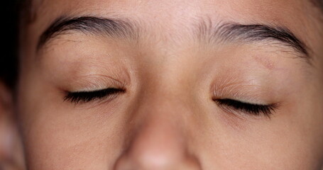 Obraz premium Little girl closing eyes in meditation. Child opening eye smiling, macro close-up