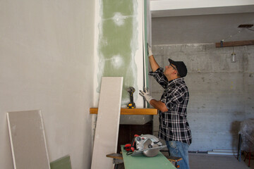Image of a handyman installing drywall panels. Do-it-yourself manual work of renovating a fireplace and house walls