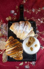 croissant and a cup of coffee on a blackboard top view