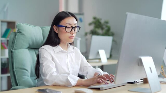 Exhausted, overworked asian office worker sitting in the workplace with severe headache massaging his head. poor vision, sore eyes Tired female employee in pain ache Stress sedentary working computer