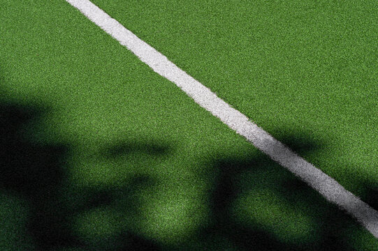 Green synthetic grass sports field with white line and shadows. Sports background for product display, banner, or mockup.