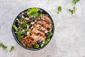 Grilled chicken breast, fillet and fresh vegetable salad of lettuce, arugula, spinach, avocado, onion and pecan nut with blueberry. Summer salad, healthy eating. Fresh healthy food.