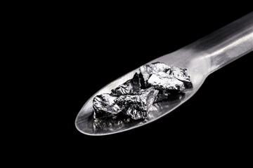 Chromium fragments on trowel, industrial use ore, metallic chemical element, isolated on black...