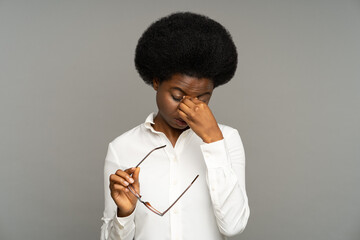 Sleepy young african business woman taking off glasses rubbing eyes feels tired after work on...