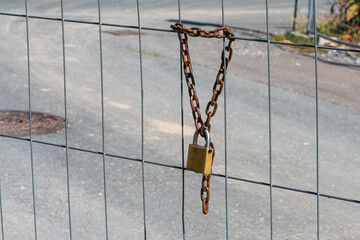 Padlock on a chain on a metal grate.