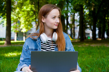 Closeup portrait of smiling caucasian female student in the park with laptop