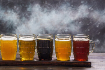Tasting set of different types of beer on a table against grunge background with copy space