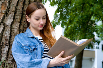 Fototapeta premium Portrait of happy student reading book outside. Education concept