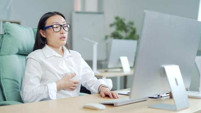 young asian female office worker having panic attack at workplace. business woman employee in the office shortness of breath, tired and sick having severe chest pain heartache at work indoor. Asia