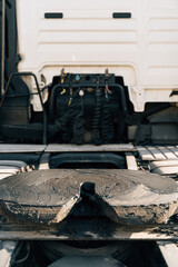 A worker smearing trailer fifth wheel coupling with lubricant oil. Semi-truck mechanical maintenance 