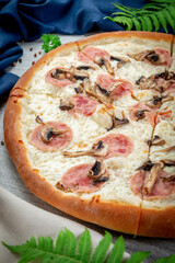Ham and mushroom pizza on a spatula. Freshly baked with parmesan, cream sauce, ham and mushrooms