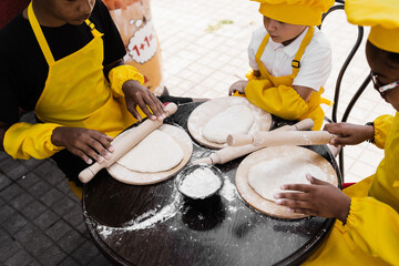 Multinational company of children cooks cooking dough close-up. Young cooks children cooking...