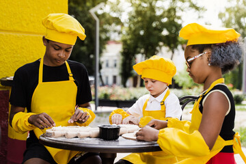 Childhood cook activity of multinational children of black african and caucasian kids. Happy company of multiethnic children cooking dough.