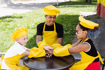 Multiracial children cook touching hands together forming pile. Friendship of multinational kids....