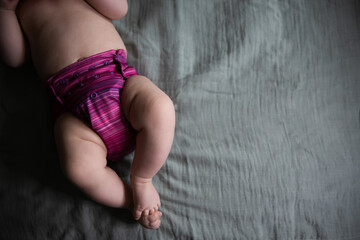 Baby in a reusable purple cloth diaper on a muslin blanket - obrazy, fototapety, plakaty
