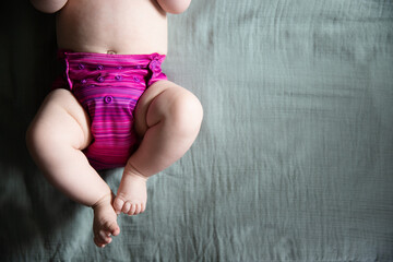 Baby in a reusable purple cloth diaper on a muslin blanket - obrazy, fototapety, plakaty