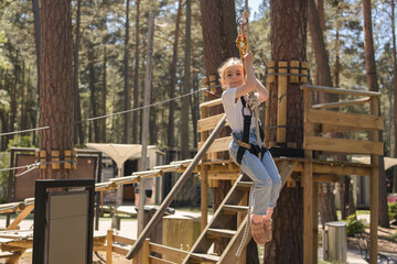 Obraz na płótnie Canvas Happy little girl enjoying activity in a climbing adventure park on a sunny day