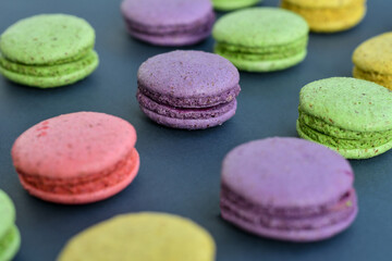 Fototapeta na wymiar Detail of multicolored macaroons in white ceramic bowl on grey background. Close up, selective focus. 
