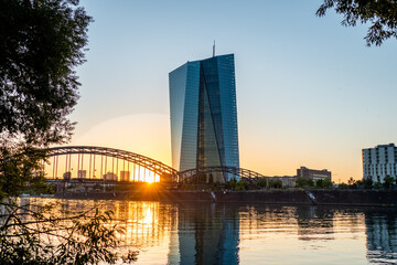 Europäische Zentralbank mit Frankfurter Skyline im Sonnenuntergang
