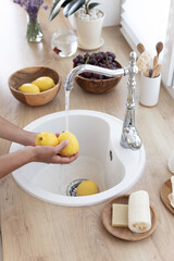 The girl washes lemons in the kitchen. Making a refreshing summer drink. Healthy food concept