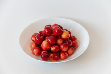 Ripe fresh cherries in a white plate on a white background. Healthy food. Close-up. Vegan breakfast.