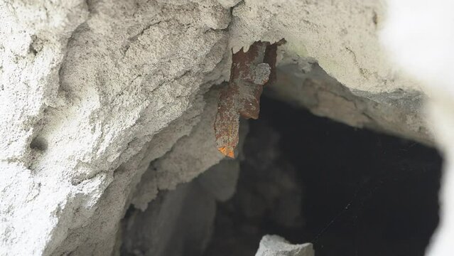 A fragment of an exploding mine sticking out in the wall. A rusty metal fragment of a mine sticking out in a brick wall after the explosion.