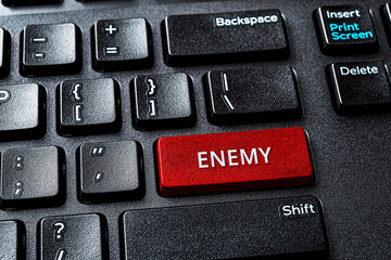Enemy word on the red enter key of a desktop pc keyboard. Laptop computer enter key with warning...