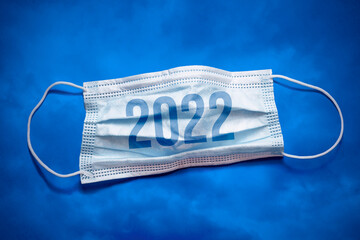 Lettering 2022 and medical mask. The return of the coronavirus. A new jump in the incidence of the...