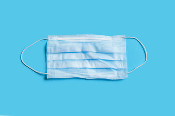 Disposable medical mask. Isolate on a blue background. Danger of viral infection. Protection...