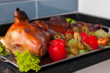 whole roasted suckling pig served on a silver platter and decorated with fruit compote