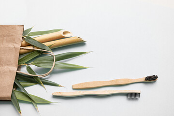 Bamboo toothbrush and eco bag on a table with copy space on a white background. Styled composition of flat lay with bamboo leaves .