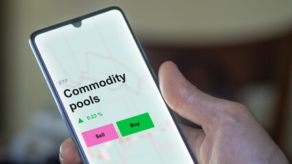 An investor's analizing the commodity pools etf fund on a screen. A phone shows the prices of Commodity pools