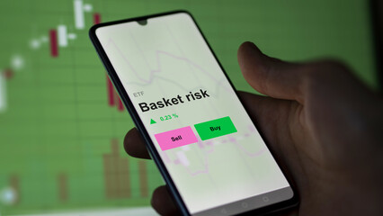 An investor's analizing the basket risk etf fund on a screen. A phone shows the prices of an ETF. 