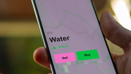 An investor's analizing the water etf fund on a screen. A phone shows the prices of Water