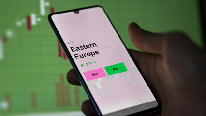 An investor's analizing the eastern europe etf fund on a screen. A phone shows the prices of Eastern Europe