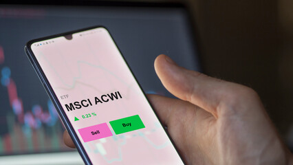 An investor's analizing the msci acwi etf fund on a screen. A phone shows the prices of MSCI ACWI