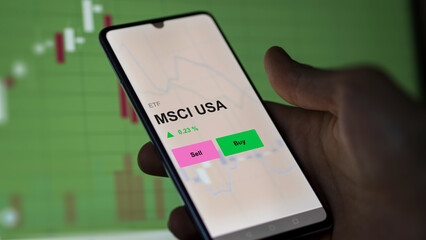 An investor's analizing the msci usa etf fund on a screen. A phone shows the prices of MSCI USA