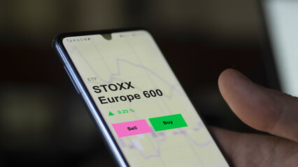 An investor's analizing the stoxx europe 600 etf fund on a screen. A phone shows the prices of STOXX Europe 600