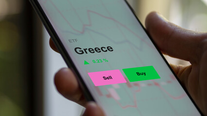 An investor's analizing the greece etf fund on a screen. A phone shows the prices of Greece